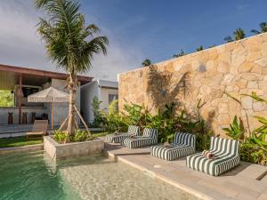 a group of lounge chairs sitting next to a swimming pool at Kala Lombok Hotel in Kuta Lombok