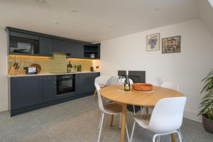 a kitchen with a wooden table and white chairs at Milsom Loft in Bath