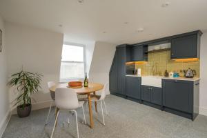 a kitchen with blue cabinets and a table and chairs at Milsom Loft in Bath