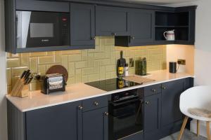 a kitchen with navy blue cabinets and a microwave at Milsom Loft in Bath +18 photos