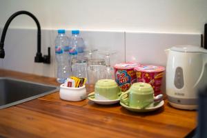 a kitchen counter with cups and snacks and a sink at Lala Panzi Villa by Manara in Jimbaran