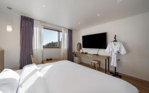 a bedroom with a white bed and a television at Incheon The Rest Hotel in Incheon