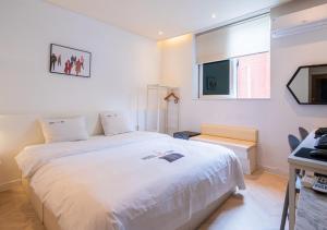 a bedroom with a large white bed and a television at Hotel YAM Yeosu Hakdong in Yeosu