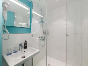 a white bathroom with a sink and a shower at Ibis Budget Leipzig City in Leipzig