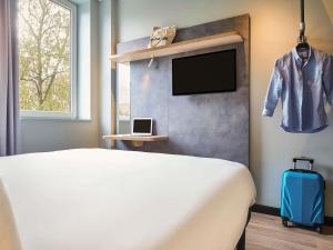 a bedroom with a bed and a tv and a suitcase at Ibis Budget Leipzig City in Leipzig