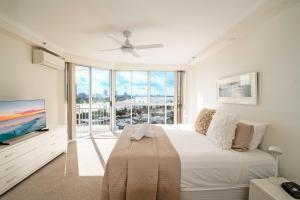 a white bedroom with a bed and a large window at Ocean Sands Resort in Gold Coast