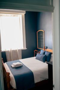 a bedroom with a bed with blue walls and a window at The Great Central Hotel in Glen Innes