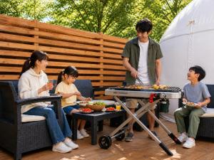 a group of people sitting around a barbecue grill at ReSchool Nasu Glamp in Nasu