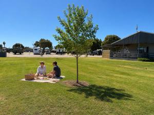 two people sitting on a blanket under a tree at Sunset Beach Holiday Park in Geraldton +61 photos
