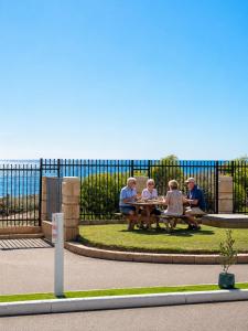a group of people sitting at a picnic table at Sunset Beach Holiday Park in Geraldton