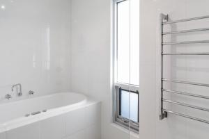 a white bathroom with a bath tub and a window at Indigo Blue in Robe +17 photos