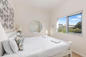 a white bedroom with a bed and a window at Indigo Blue in Robe
