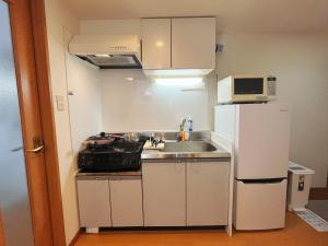 a small kitchen with a sink and a refrigerator at 一心館sakura401 in Wada