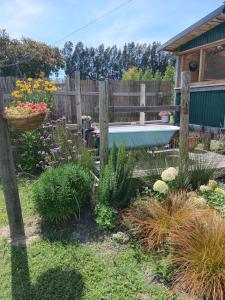a garden with a fence and a bath tub at Freefall Cottage in Haumoana