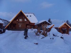 Cabaña de madera con nieve en el suelo en Vadul Lupilor, en Moisei