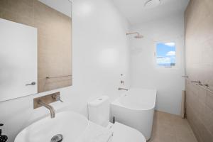 a white bathroom with a sink and a toilet at The Lookout in Diamond Beach +19 photos
