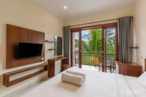 a bedroom with a bed with a television and a balcony at Sedana Cottage in Canggu