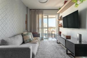 a living room with a couch and a flat screen tv at Apt Boutique Grande Florianópolis - Sua Estadia SC in São José