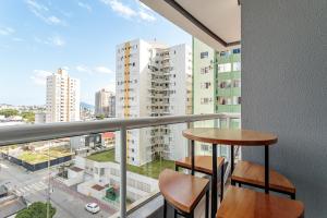 a balcony with two stools and a view of a city at Apt Boutique Grande Florianópolis - Sua Estadia SC in São José