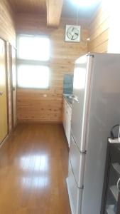 a kitchen with a refrigerator and a wooden wall at のんびれっじひなぎくａ棟 in Anazawa