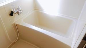 a bathtub in a bathroom with a light next to it at のんびれっじひなぎくａ棟 in Anazawa