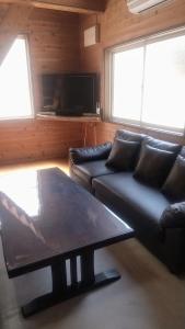 a living room with a couch and a coffee table at のんびれっじひなぎくａ棟 in Anazawa