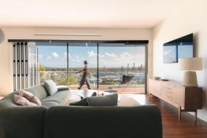 a living room with a couch and a large window at Bay Properties The Big Chill in Yamba
