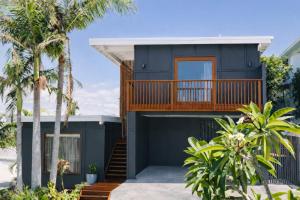 a house with a balcony and palm trees at Bay Properties The Big Chill in Yamba