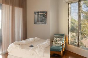a bedroom with a bed and a chair and a window at Bay Properties The Big Chill in Yamba