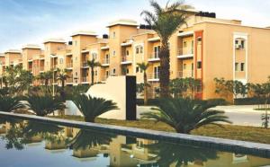 a building with palm trees in front of a swimming pool at Shubharohi stay in Chhatikara
