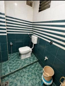 a green and white bathroom with a toilet and a bucket at Evergreen AC Bunglow in Dwarka