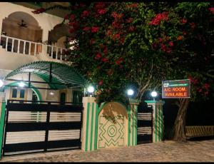 a house with a fence and a tree with a sign at Evergreen AC Bunglow in Dwarka
