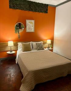 a bedroom with an orange wall with a bed and two lamps at Luca in San José +40 photos