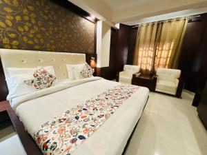a bedroom with a large bed and two chairs at Hotel Ganga Aatitheyam in Haridwār +24 photos
