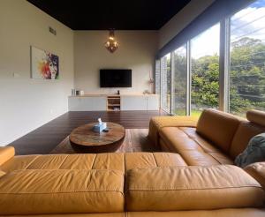 a living room with a brown couch and a table at Jasmine Escape SPA Pool Secluded Bush Views in Ellalong