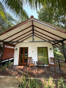a house with two chairs and a table in front of it at Walawa Reach hotel in Udawalawe