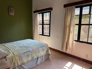 a bedroom with a bed and two windows at Casa Madero Rooms in Cuernavaca