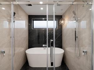 a bathroom with a tub and a shower and a sink at The Gem - 5 bedroom brand new house in Christchurch