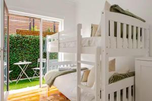 a white bunk bed in a room with a window at Manly Beachfront Stays - 3 Bedroom with Garden - Steps to Ferry, Beach, Shops & Restaurants in Sydney