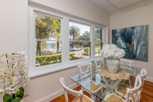 a dining room with a glass table and windows at Manly Beachfront Stays - 3 Bedroom with Garden - Steps to Ferry, Beach, Shops & Restaurants in Sydney +28 photos