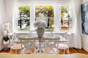 a dining room with a glass table with a vase of flowers at Manly Beachfront Stays - 3 Bedroom with Garden - Steps to Ferry, Beach, Shops & Restaurants in Sydney