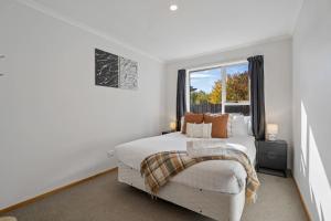a white bedroom with a bed and a window at Haven on Molyneux in Cromwell
