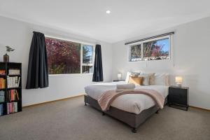 a bedroom with a large bed and two windows at Haven on Molyneux in Cromwell
