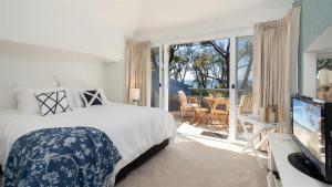 a bedroom with a bed and a tv and a balcony at Lucys at the Bay in Callala Bay