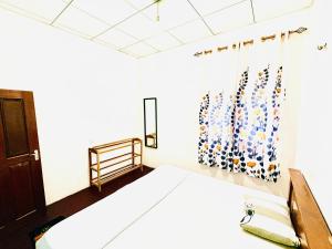a bedroom with a bed and a window with a curtain at Oli Guest House in Diyatalawa