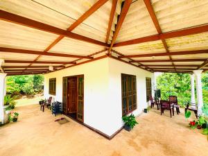 an outdoor patio with a wooden roof and chairs at Oli Guest House in Diyatalawa +9 photos
