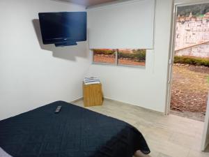 a bedroom with a bed and a flat screen tv at casa demaiz in Choachí