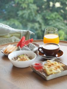 a table with a plate of food and a glass of orange juice at Amphawa Nanon Hotel in Amphawa