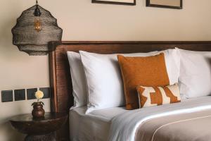 a bedroom with a bed with white pillows and a table at ALMA SHANTI Boutique Hotel in Uluwatu