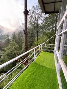 a balcony with green grass on the side of a house at jibhihomesteadcabin in Jibhi
